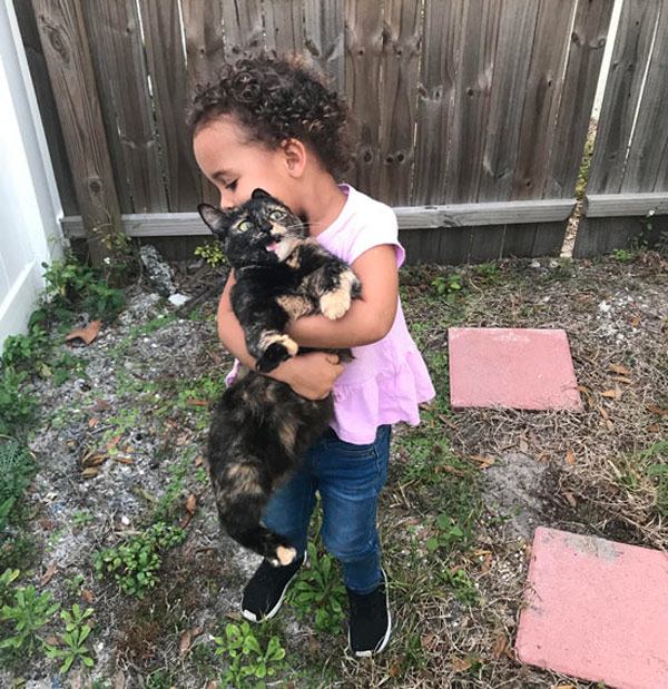 little girl holding cat tightly